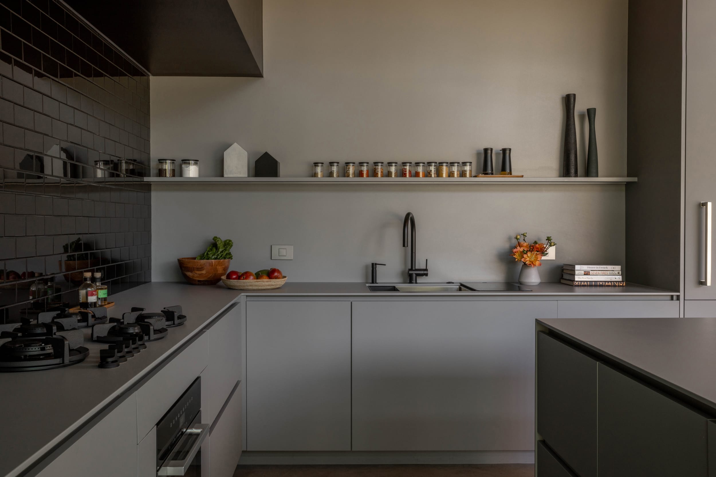 A modern kitchen with black and grey tiled walls in a modern home.
