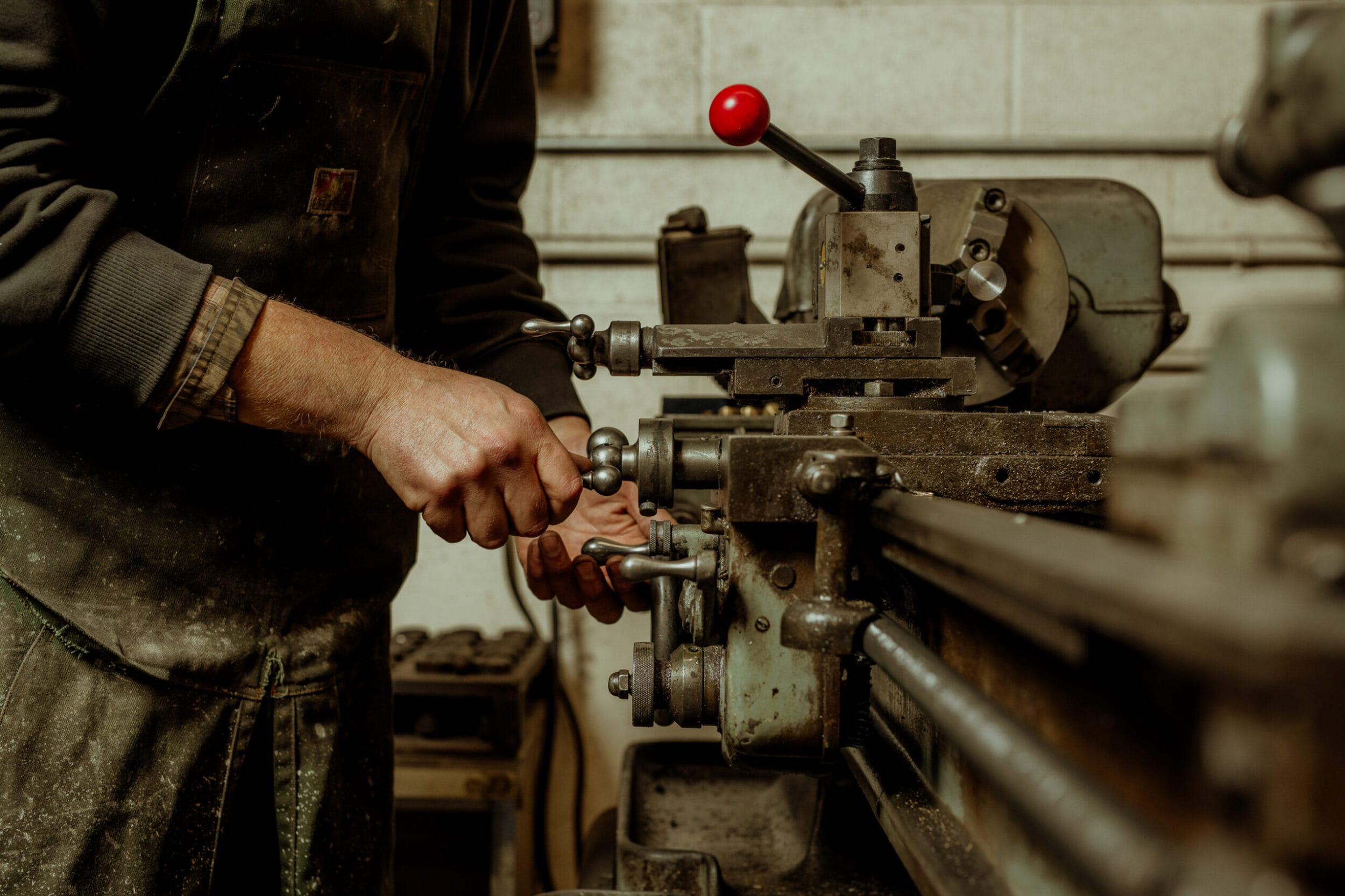 Hands working within metal shop on metal tool.